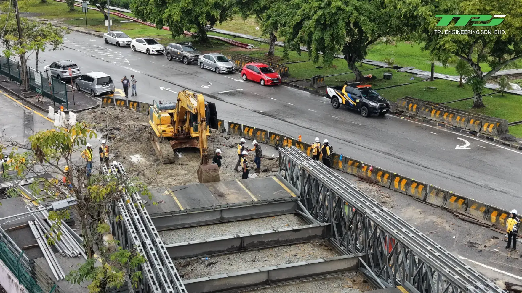 Close aerial view of workers and an excavator building the bridge deck beside the road in Seberang Jaya.