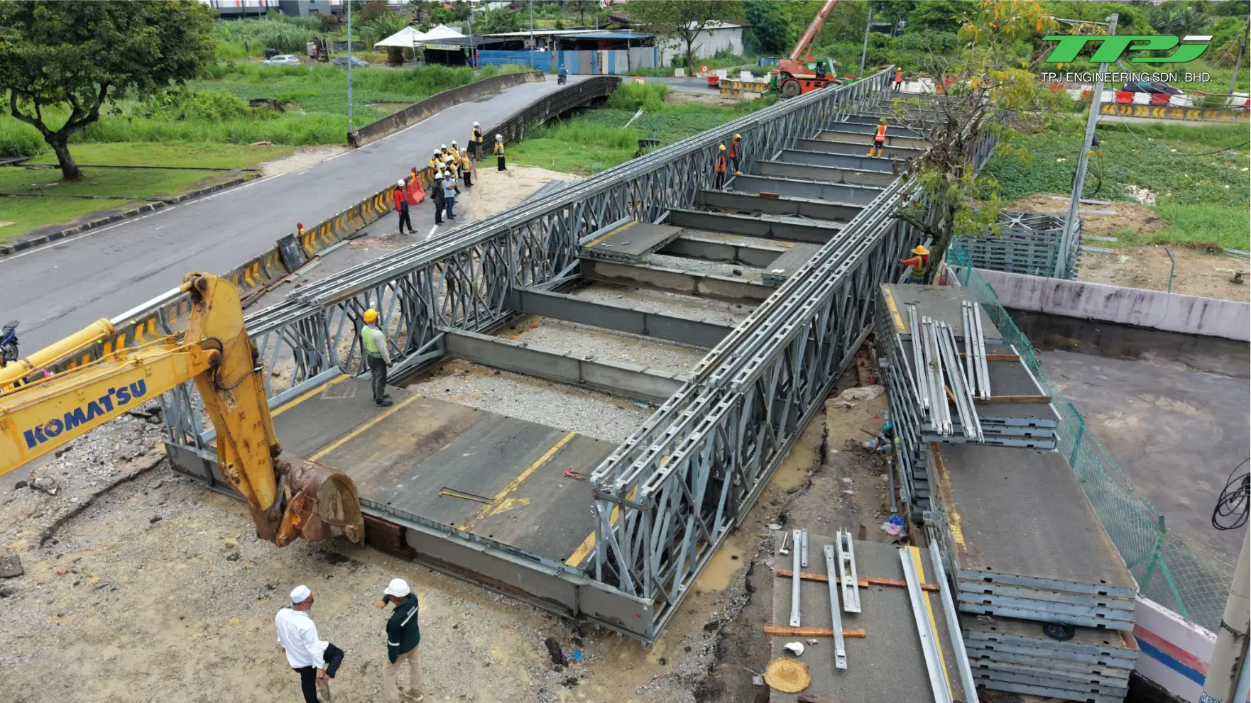 Construction crew and an excavator work on the temporary Bailey bridge deck beside the road in Seberang Jaya, Penang.