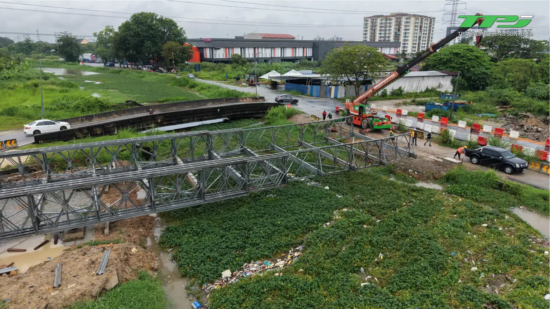 Aerial view of cranes and workers installing the Bailey bridge beside the riverside road in Seberang Jaya, Penang.