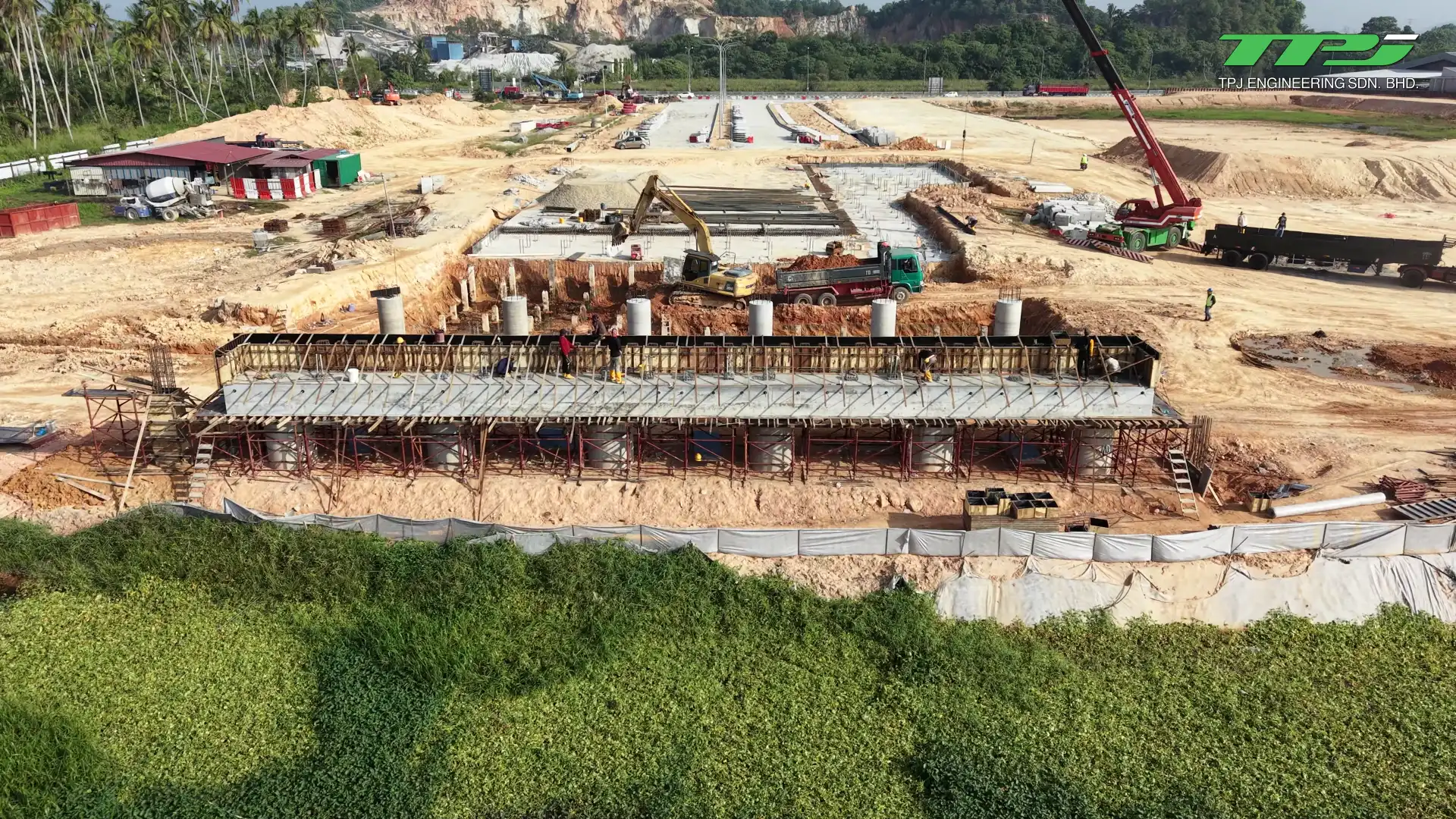 Exposed reinforcement and temporary formwork beside Sungai Binjai at the Batu Kawan bridge site.