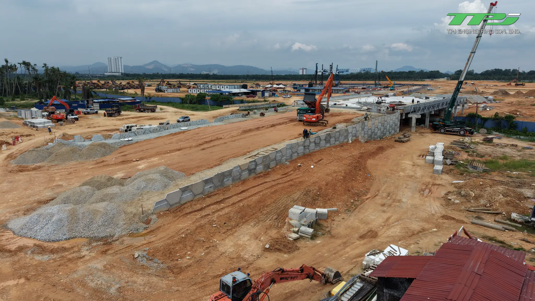 Aerial view of earth approach works leading to the Batu Kawan bridge, with retaining walls and an excavator.