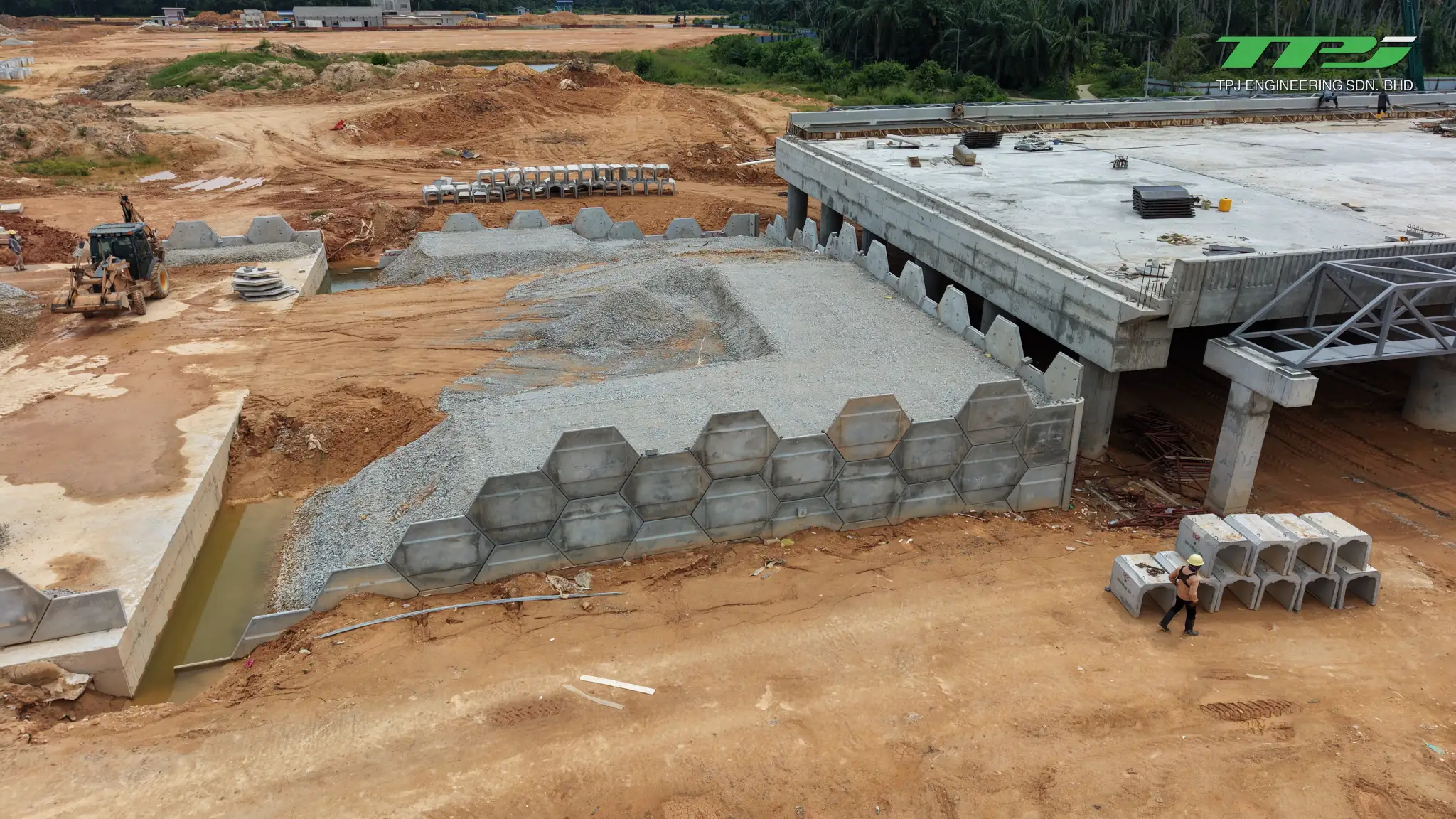 Gravel-filled approach embankment retained by hexagonal concrete panels beside the Batu Kawan bridge abutment.
