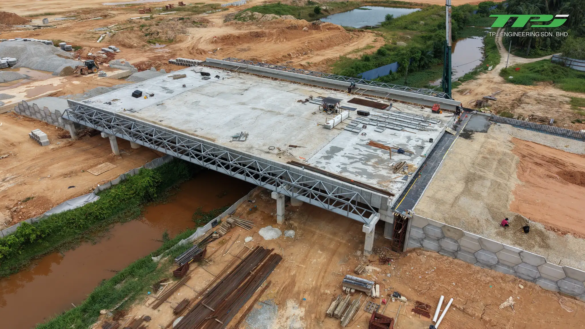Aerial view of the Batu Kawan bridge deck, retaining walls and crane beside Sungai Binjai.