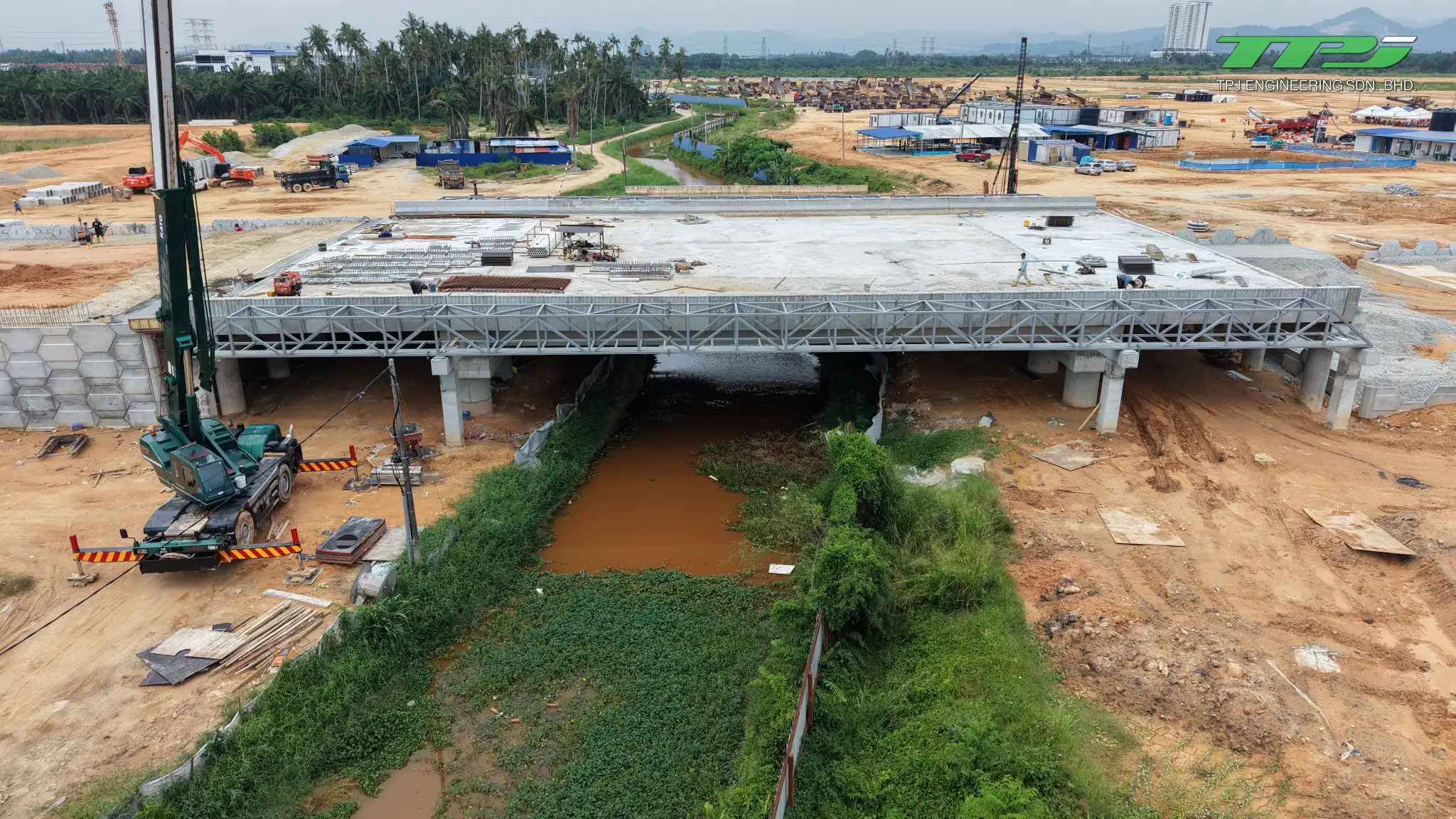 Front view of the Batu Kawan bridge deck across Sungai Binjai, with a crane and construction materials.