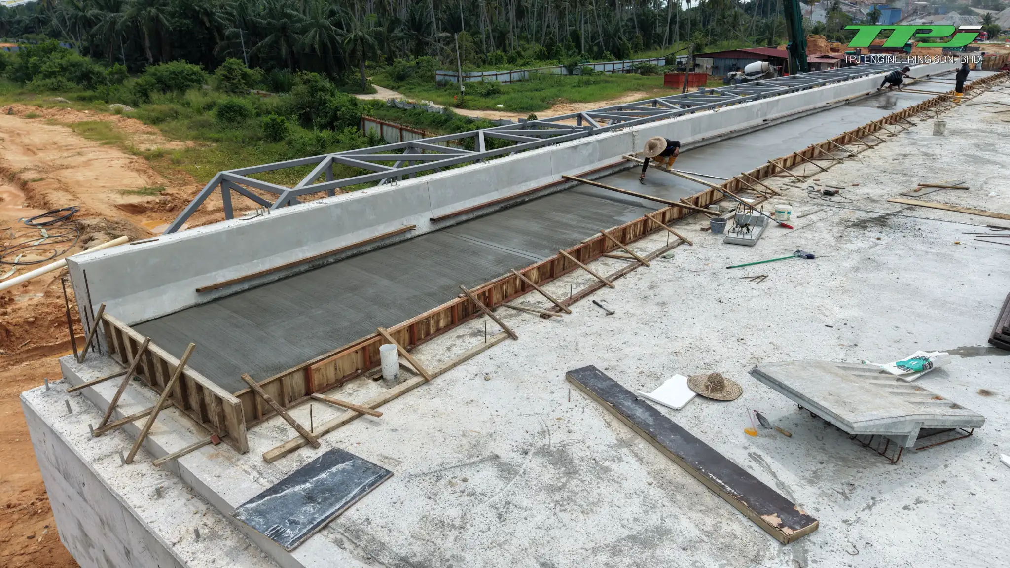 Worker beside concrete edge works and temporary formwork on the Batu Kawan bridge deck.